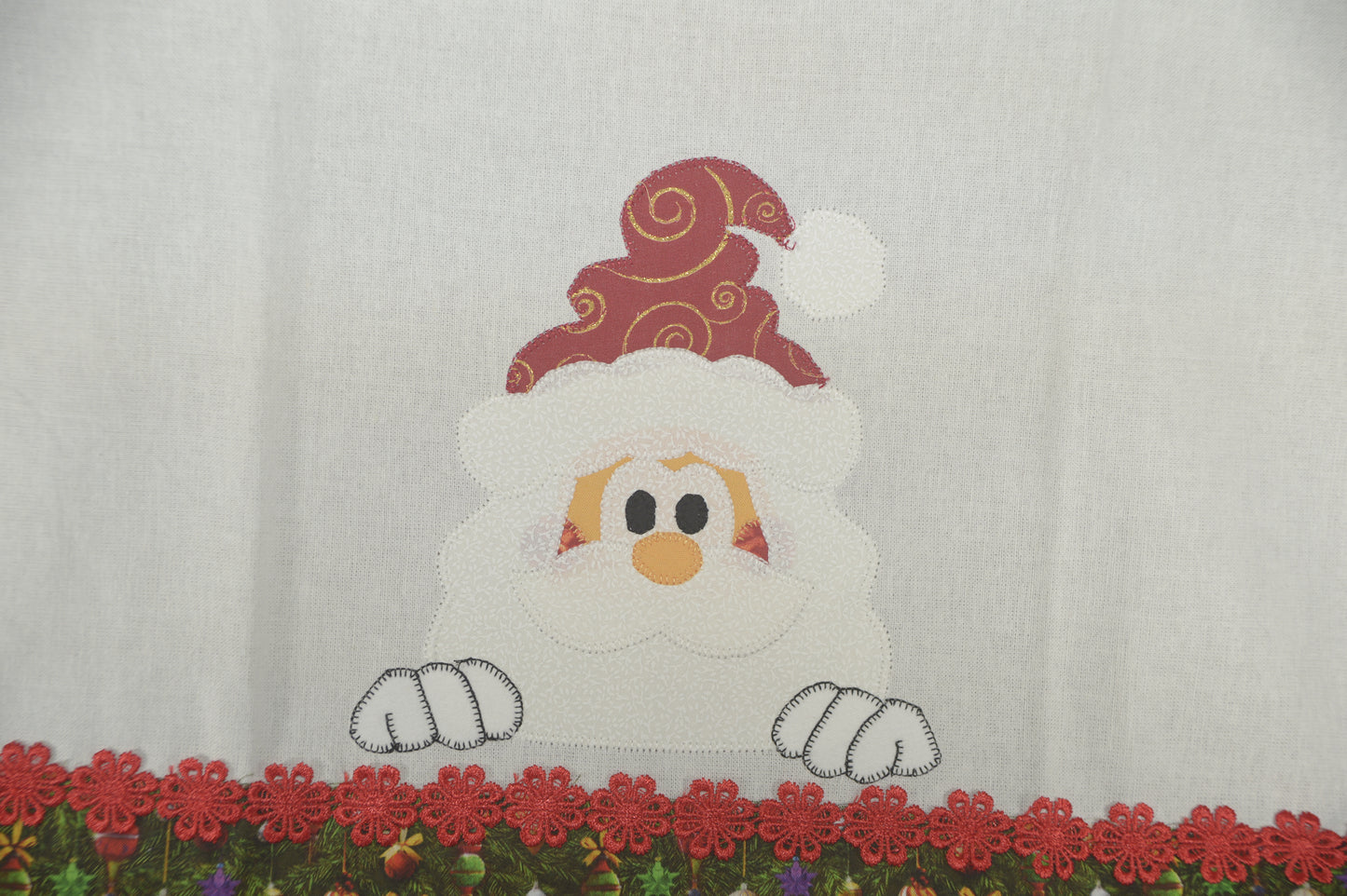 Tea Towel Santa peeking over Christmas trim.