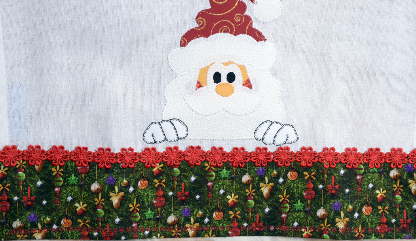 Tea Towel Santa peeking over Christmas trim.