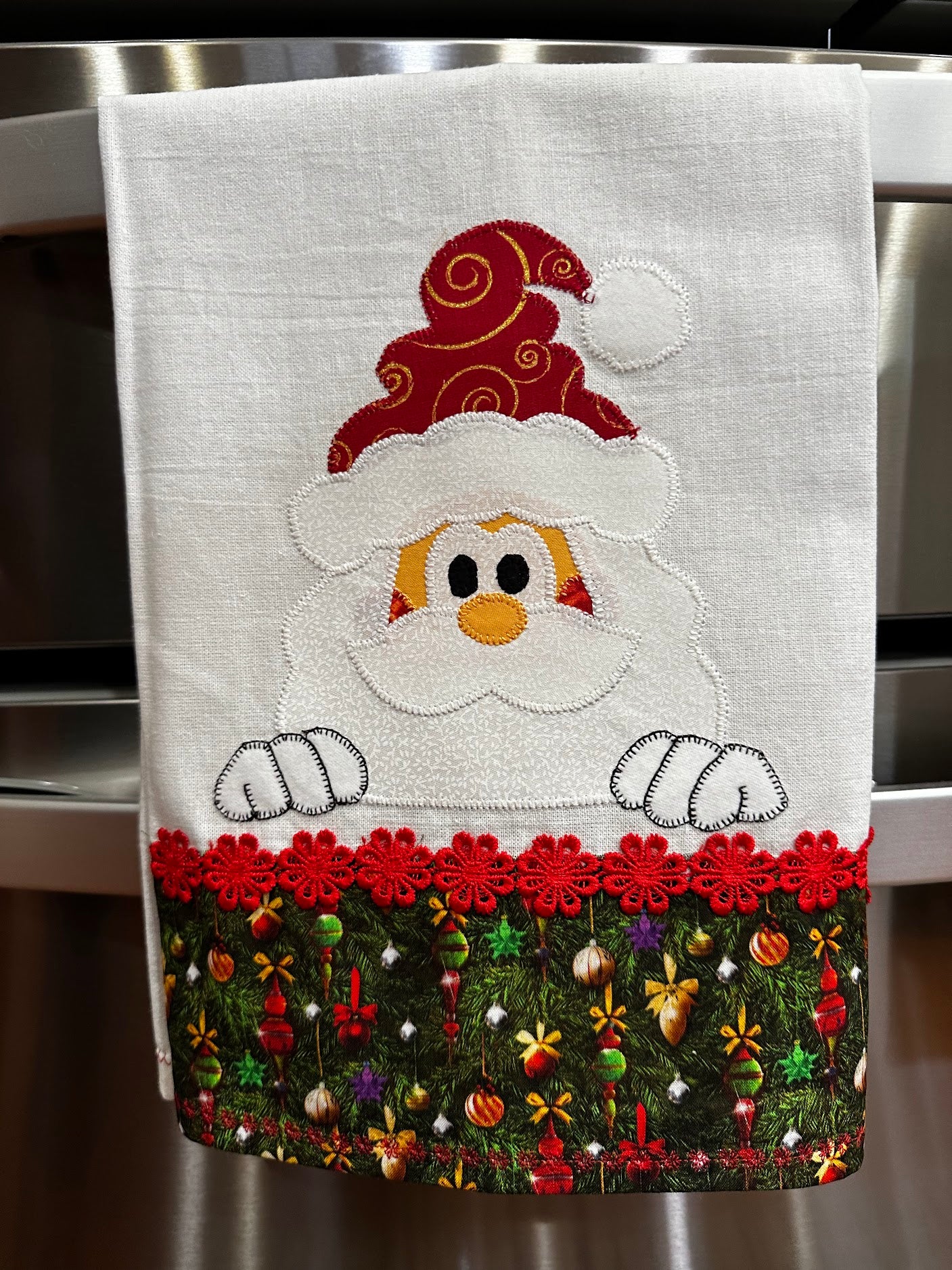 Tea Towel Santa peeking over Christmas trim.